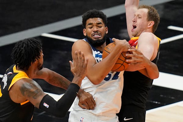 Wolves star Karl-Anthony Towns pulled down a rebound between Utah’s Derrick Favors, left, and Joe Ingles during the second half Saturday night.