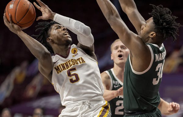 Above, Marcus Carr (5) of Minnesota attempted a shot while defended by Julius Marble II (34) of Michigan State in the first half. Top, Liam Robbins (0