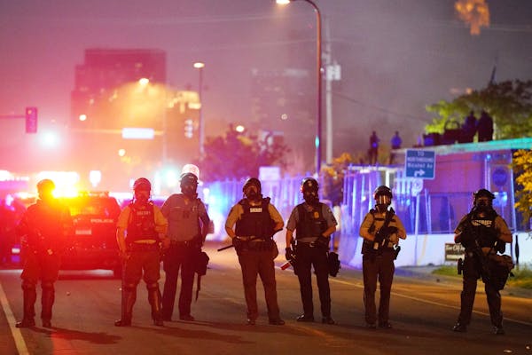 Police stood guard after using tear gas to clear a group of hundreds of protesters that had gathered near the Minneapolis Police 5th Precinct in the h