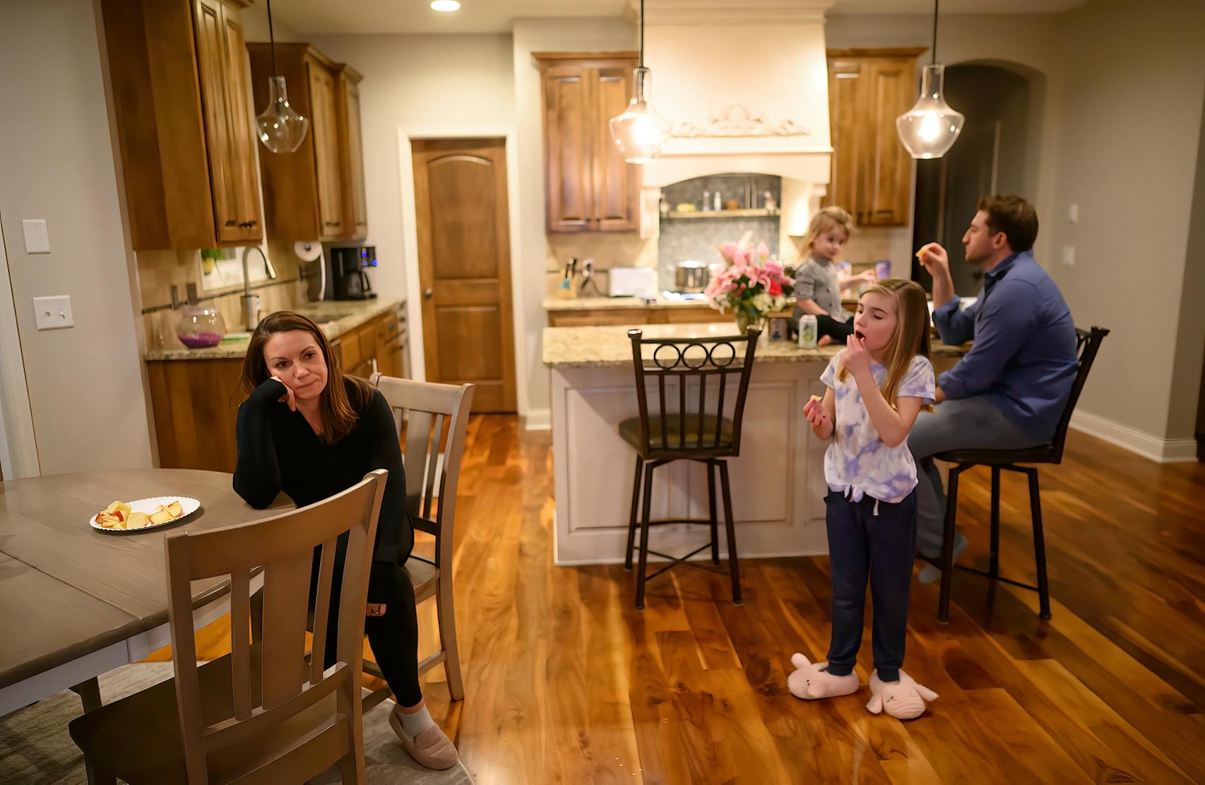 Holly Vilione looked on as her daughters Nora, 2, Mya, 8 and husband, Chris Vilione, snacked in the kitchen a few hours after Holly returned from another difficult day working in the ICU.