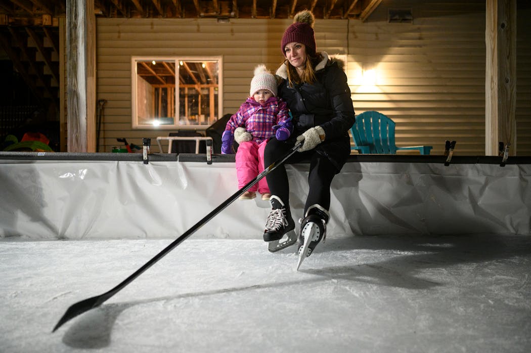 Holly Vilione sat with her 2-year old daughter, Nora, while taking a break from playing some backyard hockey with her kids and nieces in late January. 