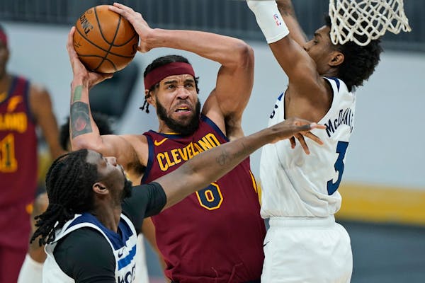 Cleveland Cavaliers’ JaVale McGee, center, drives to the basket against Minnesota Timberwolves’ Naz Reid, left, and Jaden McDaniels , right.