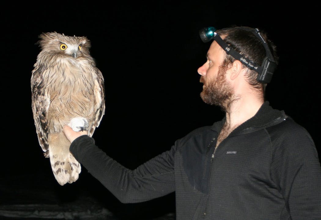 Jonathan Slaght and a fish owl.