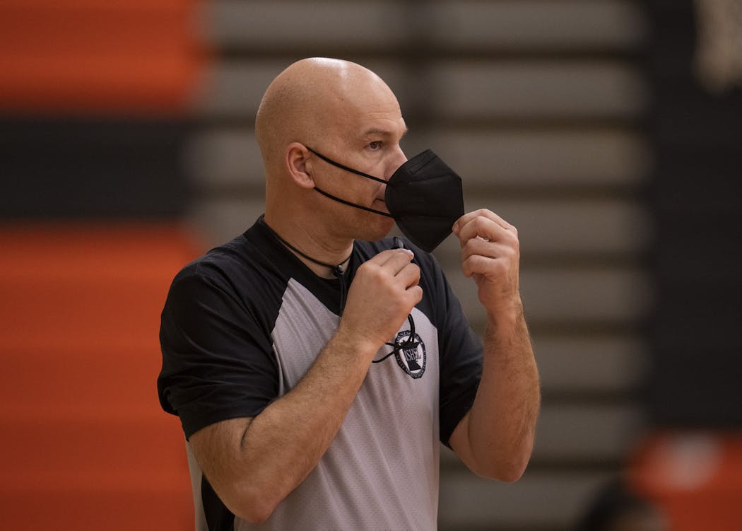 Referee Denny Misener replaced his whistle under his mask while officiating the game between Anoka and Osseo.