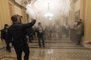 Smoke fills the walkway outside the Senate Chamber as insurrectionists loyal to President Donald Trump are confronted by U.S. Capitol Police officers 