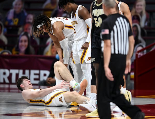Gophers center Liam Robbins (0) grabbed his lower left leg after a hard fall in the second half against Purdue earlier this month.
