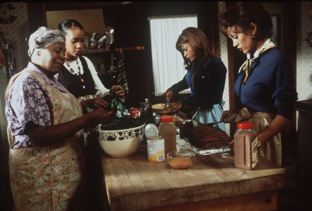Irma P. Hall, left, as the family matriarch helps her daughters played by Vivacia A. Fox, Nia Long and Vanessa L. Williams, prepare for the weekly family dinner in 'Soul Food.'