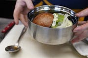 Dan Schmit, Wise Acre executive chef, prepares a Scottish Highland beef burger in a reusable stainless steel container.