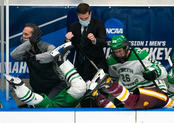 (Left) North Dakota Fighting Hawks forward Riese Gaber (17) and UMD Bulldogs defenseman Louie Roehl (6) fell over the boards and into the North Dakota