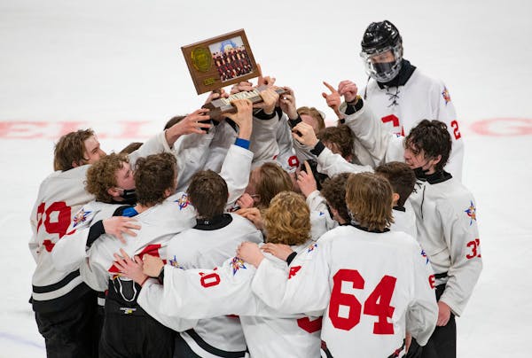 Gentry Academy players raised their trophy after winning the boys’ hockey Class 1A state championship 