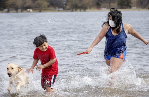 Owen Montero, 7, left, and Dulce Pereanez, 11, and their dog Bruno joined many who flocked to Lake Nokomis on Monday. Pereanez said the water was cold