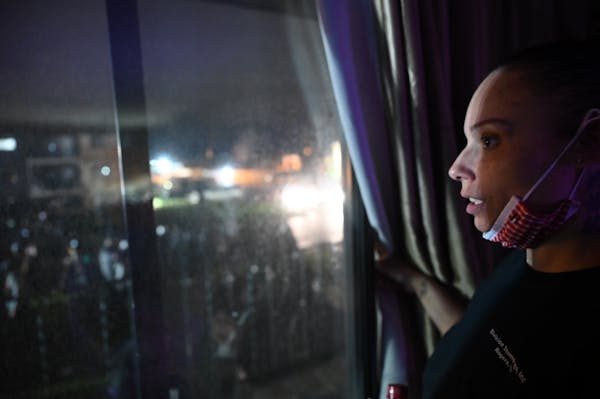Angela Johnson, who lives across the street from the Brooklyn Center Police Department, watches the chaos from her window Wednesday night.