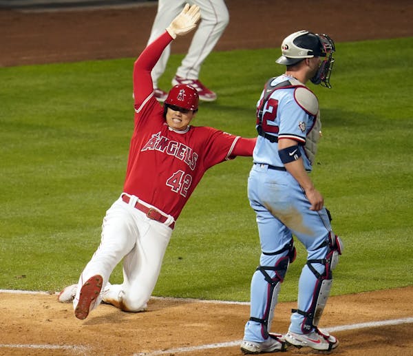 Los Angeles Angels’ Shohei Ohtani scores past Minnesota Twins catcher Mitch Garver on a single from Mike Trout during the sixth inning of a baseball
