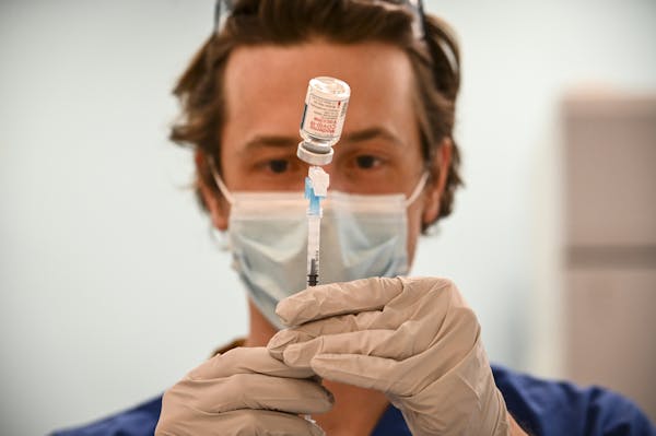 Kirk Randall, a nurse with Blue Cross and Blue Shield of Minnesota, filled a syringe with a dose of the Moderna COVID-19 vaccine at the site of the fo