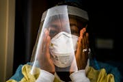Nurse manager Nkeiru Adoga adjusted her N95 mask while putting on PPE to visit a COVID-19 patient in a stepdown unit at Regions Hospital in St. Paul o