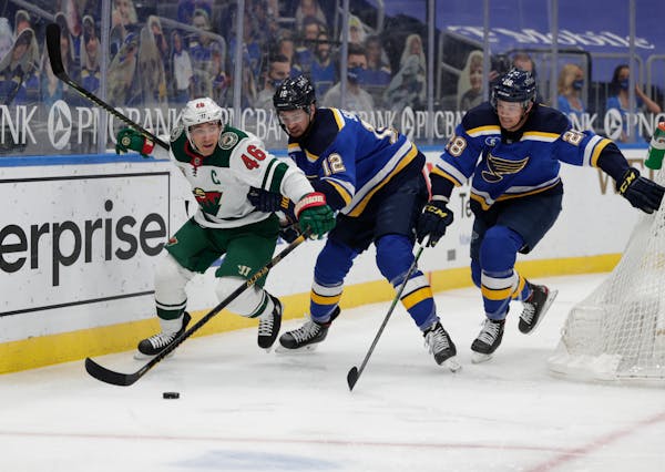 The Wild’s Jared Spurgeon battles St. Louis Blues’ Zach Sanford and Mackenzie MacEachern for the loose puck in the second period