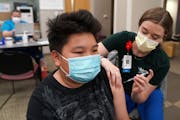 Kuabcag Yang, 13, of Brooklyn Park, got his first dose of the Pfizer COVID-19 vaccine from nurse Jenn Doble on Thursday at Children’s Minnesota.