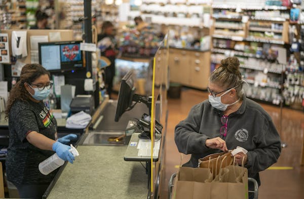 Cindy Lambing of Minneapolis completed her shopping at Linden Hills Co-op in Minneapolis last spring as cashier Sareena Tippett sanitized the checkout