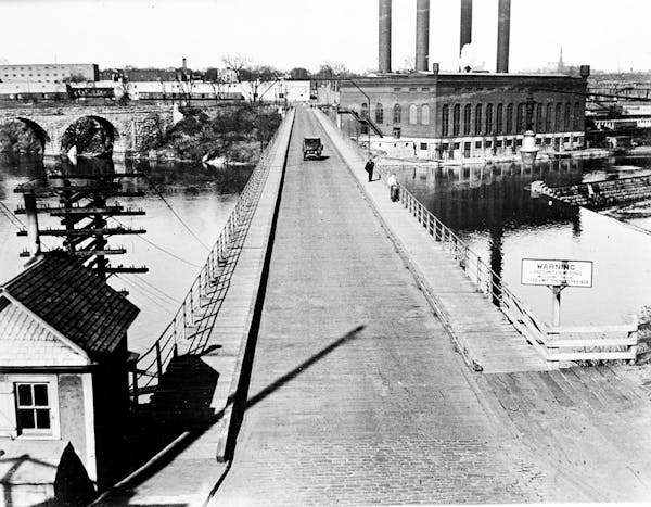 A view of the 10th Avenue Bridge looking east in the 1920s. The Twin City Rapid Transit Steam Power Plant is in the right background, the Stone Arch B