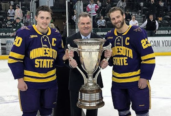 WCHA Commissioner Bill Robertson presented the MacNaughton Cup to Minnesota State Mankato’s Marc Michaelis, left, and Nick Rivera in 2019.