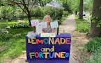 Photos by IMANI CRUZEN@Caption:Willa reveals fortunes on the other side of colorful art she hangs above her lemonade stand.