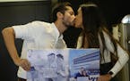 Doctor David Vallejo and his fiancee Doctor Mavelin Bonilla hold photos of themselves working, as they kiss at their home in Quito, Ecuador, Wednesday