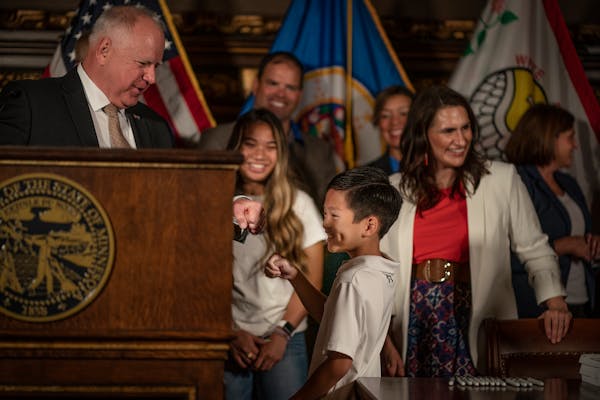 Gov. Tim Walz’s gave Dylan Nguyen, 9, a fist bump after he signed a $52 billion state budget bill. Dylan’s mom, Hue Nguyen, is the deputy chief of