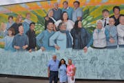 A mural commissioned by Laura Murvartian, center, with her parents, celebrates the welcoming arms that the immigrant felt growing up in St. James, Min