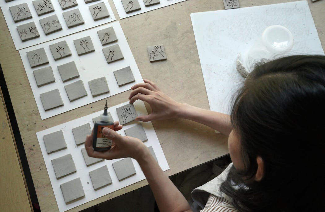 Youmee Lee worked on clay tiles in the Anderson Center Studio.