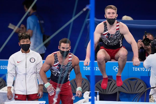 Gymnasts from the United States, from left, Yul Moldauer, Samuel Mikulak, and Shane Wiskus watch teammate Brody Malone performing on the horizontal ba