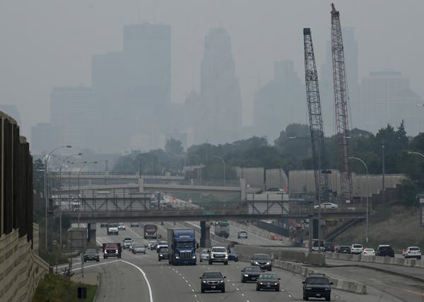Traffic moved along Interstate 35W, with downtown Minneapolis enveloped by a smoky haze, as seen from the East 46th Street overpass. 