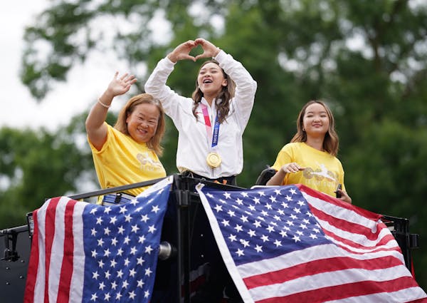 Sunisa Lee, center, with her mom Yeev Thoj and sister Shyenne Lee, waved to the crowds during a parade Sunday in the East Side St. Paul neighborhood w