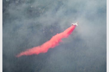 An aircraft dropped red fire retardant onto the Greenwood Fire on Tuesday, as seen from an airplane above the temporary flight restriction zone.