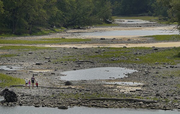 A woman and children explored a dried-up channel of the Mississippi River in Mississippi Gateway Regional Park in Brooklyn Park on Tuesday, amid the o