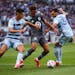Minnesota United midfielder Hassani Dotson (31), center, tries to dribble past Sporting Kansas City defender Luis Martins (36), right, and Sporting Ka