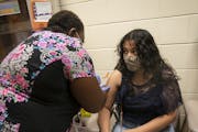 Registered nurse Yvonne Akufongwe gave Jennifer Guiterrez, 15, her second Pfizer vaccine at a community vaccination clinic at Gordon Parks High School