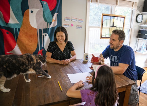 Asuka Kakitani and JC Sanford were interrupted by their cat Sora while spending time with their daughter playing a card game at home in Northfield.