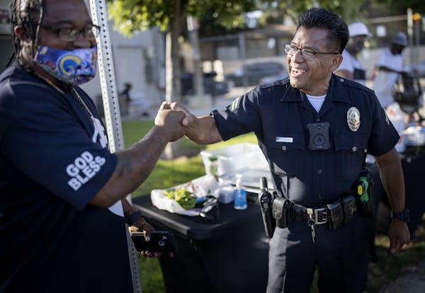 Tyrice Cagle, a community intervention worker, was greeted by officer Abel Estopin before a movie night at a Los Angeles park.