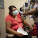 RN Yvonne Akufongwe gave Patricia Bonilla her first Pfizer vaccine as Bonilla’s 3-year-old son watched at a community vaccination clinic in St. Paul