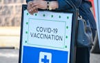 A woman leans on a COVID-19 vaccine registration sign at a back-to-school vaccine fair in West Baltimore, Maryland. Because a vaccine is not yet autho
