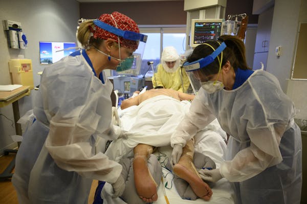 Respiratory therapist Tamara Eirten, center, worked on turning an intubated COVID-19 patient’s head as nurses Jessica Hultgren, left, and Amy Berwal