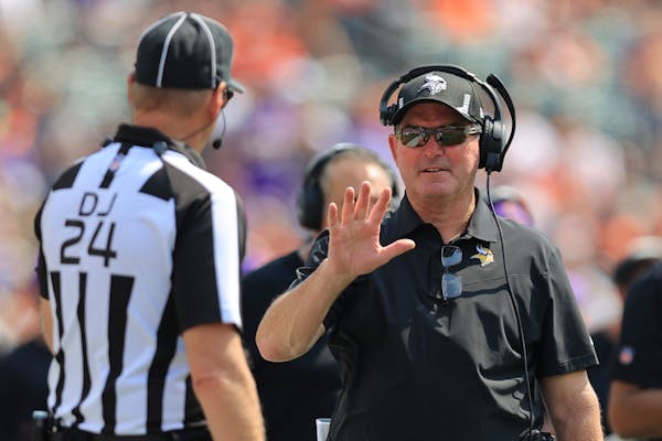 Minnesota Vikings head coach Mike Zimmer talks with an official in the first half of an NFL football game against the Cincinnati Bengals, Sunday, Sept