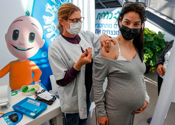 A health worker administers a dose of the Pfizer-BioNtech COVID-19 coronavirus vaccine to a pregnant woman at Clalit Health Services, in Israel’s Me