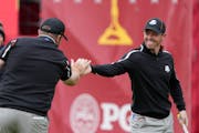 Team Europe’s Tyrrell Hatton congratulates Rory McIlroy after a putt on the ninth hole during a practice day at the Ryder Cup on Thursday. 