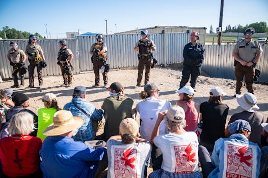 Law enforcement agents formed a line in front of a wall of protestors who sat just in front of a locked gate at an Enbridge pump station in June.