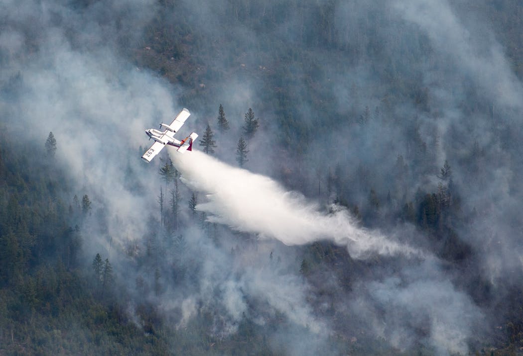 An aircraft drops water scooped from nearby Sand Lake onto the Greenwood Fire in August 2021.