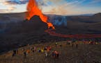 People watch as lava flows from an eruption from the Fagradalsfjall volcano on the Reykjanes Peninsula in southwestern Iceland on May 11, 2021. 