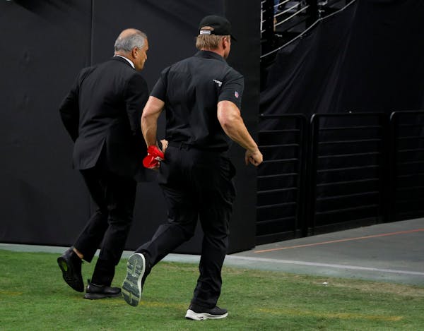 Las Vegas Raiders director of team security Bob Stiriti, left, and former Raiders head coach Jon Gruden run off the field after the team’s 20-9 loss