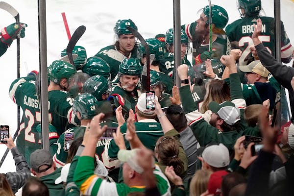 Wild players and fans along the boards celebrate following an overtime goal by Ryan Hartman against the Ducks