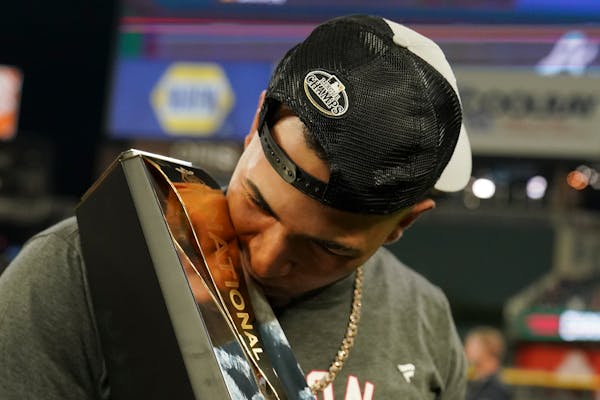 Atlanta Braves left fielder Eddie Rosario kisses the Most Valuable Player trophy after winning Game 6 of baseball's National League Championship Serie
